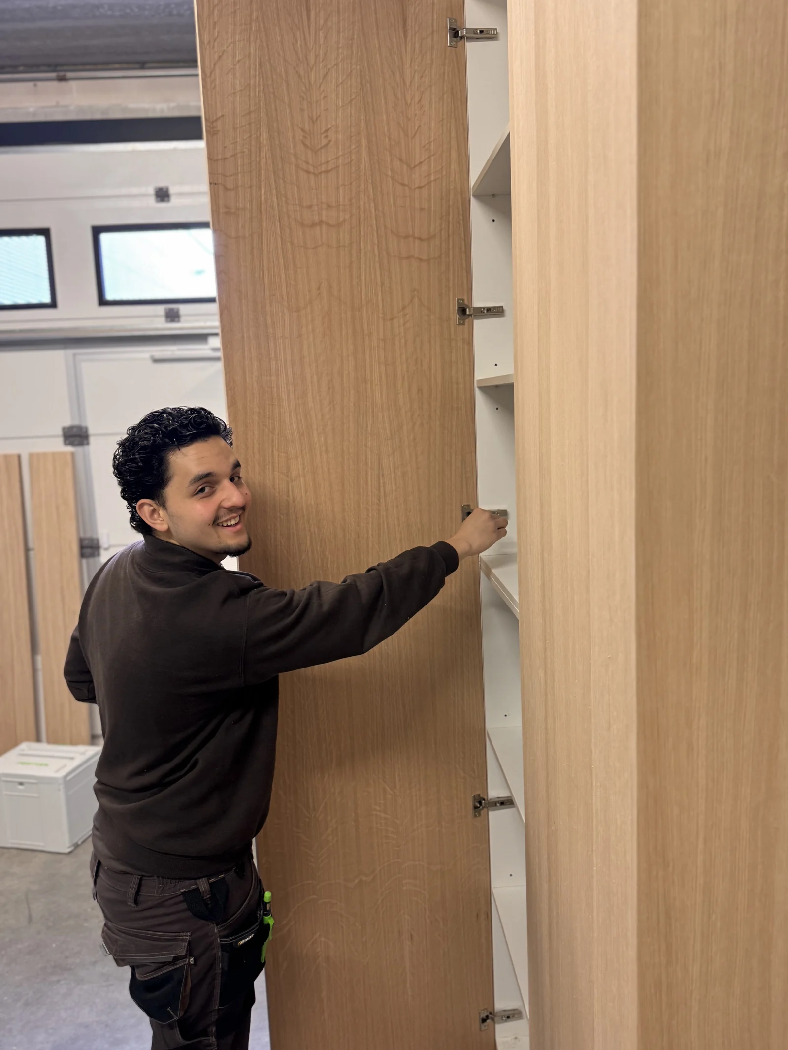 Santiago stelt het scharnier van een houten maatwerkkast af in zijn werkplaats